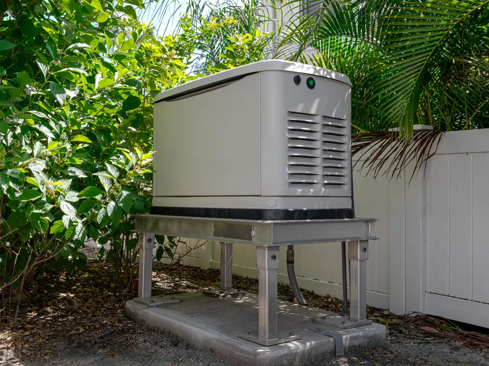 Whole-house standby generator mounted on an elevated stand in a residential backyard
